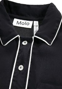 Svart skjorta med krage, vit kantnigning och knäppning. Etiketten visar "Molo," vilket indikerar storlek 122/128. Texturerad tygdetalj synlig.