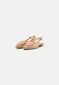 Beige slingback flats made of soft suede, featuring a pointed toe, decorative upper flap, and a small block heel.