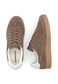 Baskets en suède marron avec une semelle en caoutchouc gum, dotées d'un laçage, d'un col rembourré et d'un accent de talon blanc contrastant.