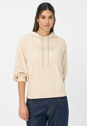 Sweatshirt beige à coupe décontractée, avec capuche à cordon, manches à poignets et logo "Bronx" sur le devant. Assorti avec un jean en denim foncé.