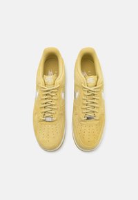 Yellow suede Nike Air Force sneakers with a perforated toe box, white Swoosh logo, and matching laces, featuring a cushioned interior.