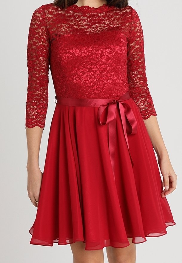 Robe rouge avec des manches en dentelle trois-quarts, un corsage ajusté et une jupe fluide. Comprend une ceinture en satin et une texture de jupe superposée.