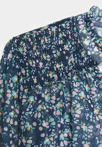 Tessuto floreale navy con dettagli smock e cucitura arricciata sulla spalla e nella parte superiore del petto della blusa.