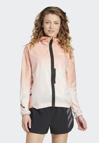 Veste légère à capuche dégradée de couleur pêche et blanc. Comprend une fermeture éclair à l'avant, des finitions noires et une poche poitrine pour le rangement.
