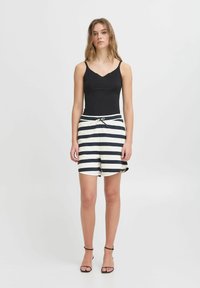 Zwarte mouwloze top met een V-hals, gecombineerd met crèmekleurige en marineblauwe gestreepte shorts met een trekkoord in de taille en zijzakken.