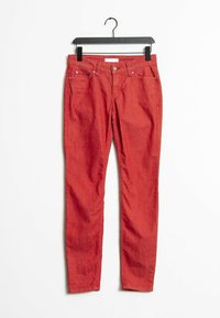 Červené skinny džíny s pěti kapsami, zipem a poutky na pásek. Hladká textura a rovnoměrná barva s jemnými detaily stehu.