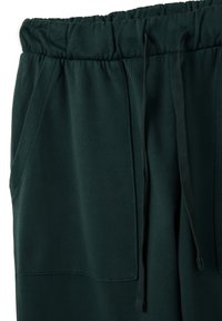 Donkergroene sweatpants met een zachte textuur, elastische tailleband en trekkoord. Bevat zijzakken en heeft een gladde, onopgesmukte uitstraling.