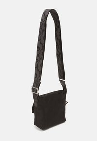 Black crossbody bag with a textured surface, featuring a patterned adjustable strap, silver hardware, and a compact rectangular shape.