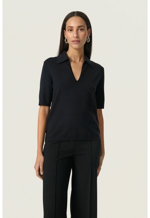 Navy short-sleeve top with a V-neck and collared design, made from a smooth fabric. Paired with black tailored trousers.