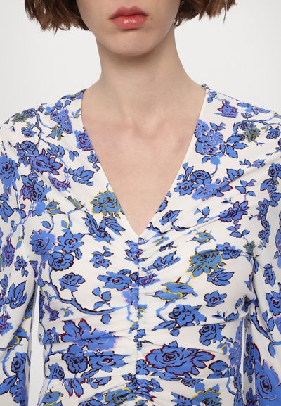 Floral top featuring a white base with blue and green flower patterns, gathered detailing at the neckline, and a V-shaped collar.
