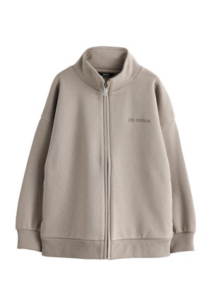 Veste beige à fermeture éclair avec col montant, poignets et ourlet côtelés, et texte "LTD. EDITION" brodé sur la poitrine gauche.