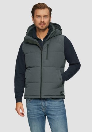 Graue Steppweste mit Kapuze, gestepptem Design, Reißverschluss vorne, seitlichen Taschen und einem Logo-Patch am Saum. Gestylt über einem dunkelblauen Sweater.