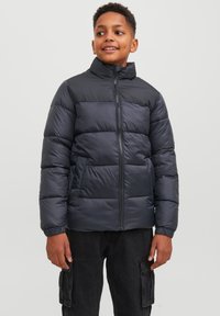 Podložena puhovka v temno modri barvi z visokim ovratnikom, ki ima sprednji zadrgo in elastične manšete, zasnovana z vodoravnimi ožjimi delnimi sekcijami.