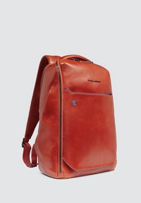 Mochila de cuero roja con un diseño elegante, textura suave, detalles en azul y cierre con cremallera. Cuenta con correas acolchadas para mayor comodidad.