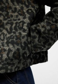 Leopard print jacket featuring a soft, textured fabric in shades of black, gray, and brown, with a prominent pocket detail on the side.