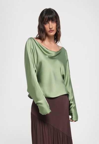 Grøn satin langærmet top med en bred bådudskæring, der har en glat tekstur og løs pasform, parret med en brun nederdel med folder.