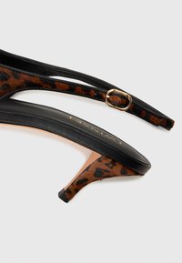 Leopardmønstret åpne tå hæler med svarte skinnstropper. Har en slank silhuett, myk tekstur og et lite hæl-design.
