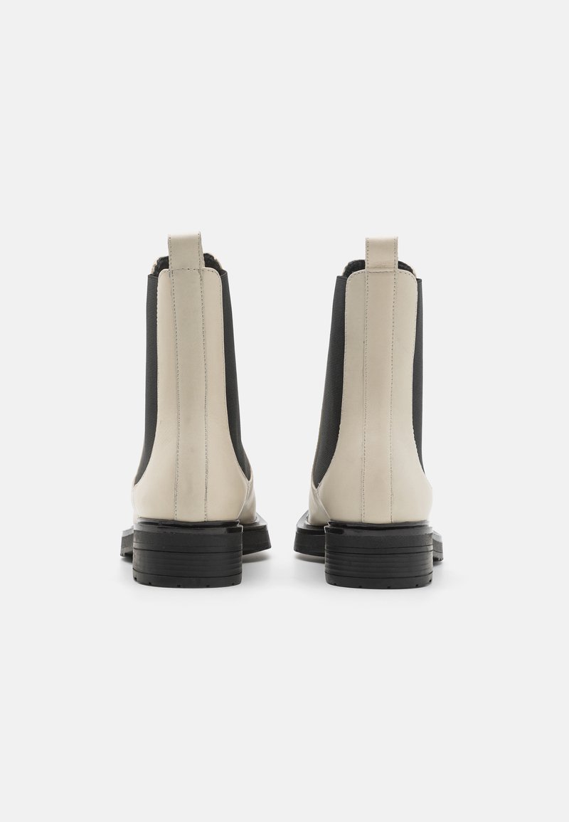 Beżowe i czarne skórzane botki za kostkę z elastycznymi panelami po bokach, z czarnymi, warstwowymi obcasami i gładką fakturą. Wyróżniają się subtelnymi detalami przeszyć.