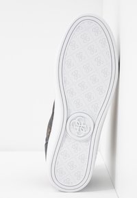 Czarne sportowe buty z białą gumową podeszwą. Podeszwa ma wzór logo wytłoczonego i teksturowany bieżnik. Akcentowane cienkimi białymi paskami po bokach.