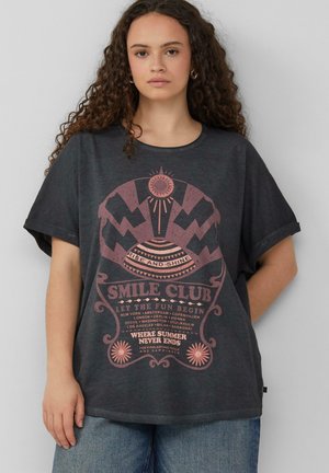 T-shirt oversize gris foncé à manches courtes ; présente un imprimé graphique rose avec du texte et des motifs géométriques, col rond et coupe décontractée.