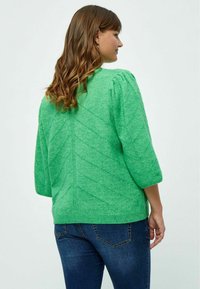 Grüner Strickpullover mit kurzen Puffärmeln, der ein strukturiertes Zickzackmuster aufweist. Der Rücken hat einen gerippten Halsausschnitt und Bündchendetails.
