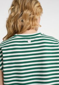 Grøn- og hvidstribet T-shirt med rund halsudskæring, korte ærmer og en lille knapdetalje bagpå. Blødt bomuldsstof.