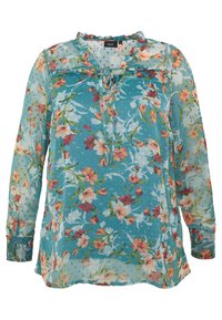 Blouse florale en tissu léger bleu clair avec des motifs de fleurs roses et jaunes. Présente un col froncé et des détails de boutons. Manches longues.