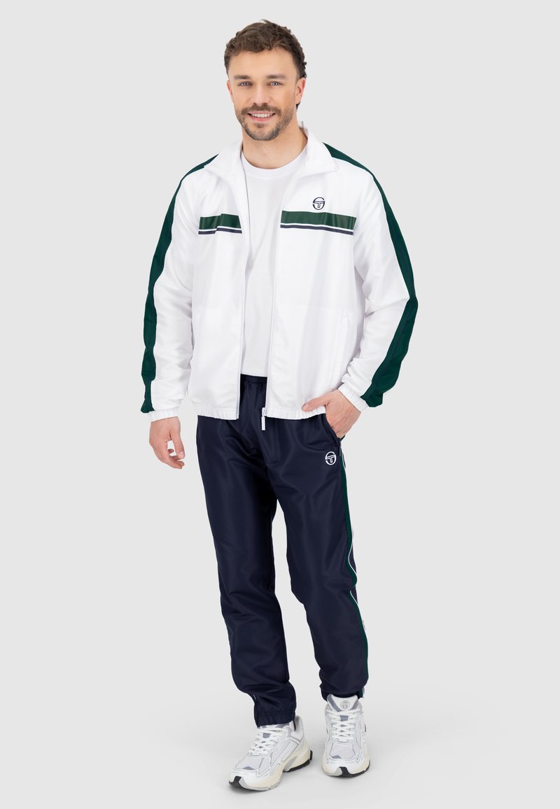 Trackjacke in Weiß mit grünen Streifen, kombiniert mit marineblauen Jogginghosen mit Logo. Glatter Stoff, lockere Passform und elastische Bündchen.