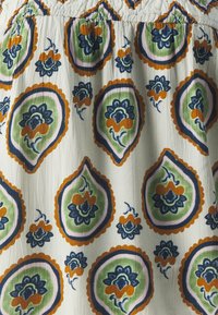Tissu blanc présentant un motif répétitif de formes paisley colorées en vert, bleu, orange et rose, avec une surface texturée.