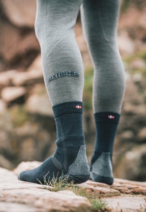 Schwarze und graue Socken mit strukturierten Mustern und gerippten Bündchen. Mit einem kleinen Flaggenemblem und "EXTREME" Branding an der Seite.