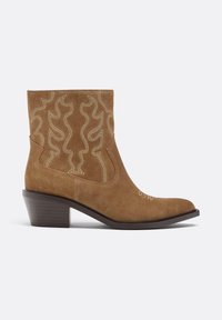 Brązowe zamszowe botki za kostkę z ostrym noskiem, szczegółowym przeszyciem w falisty wzór i niskim, warstwowym obcasem.