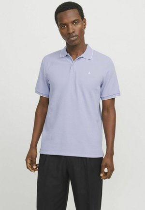 Polo shirt in light lavender with a textured fabric, short sleeves, and a white trim along the collar and sleeves, featuring a small logo.