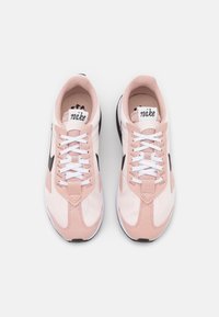 Vaaleanpunaiset urheilulenkkarit, joissa on verkko- ja nahan eli mokkanahkamateriaaleja, valkoiset nauhat, musta swoosh-logo ja teksturoitu valkoinen pohja.