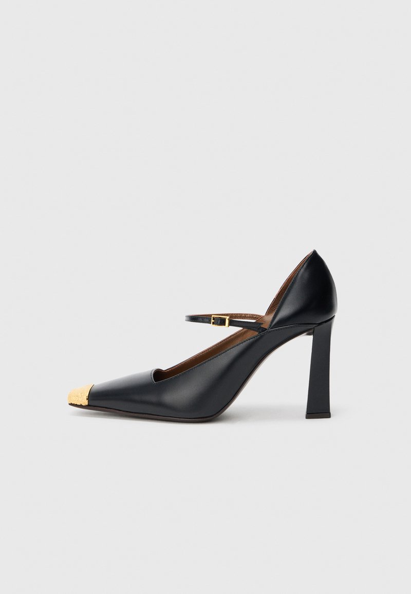 Pantof negru din piele cu vârf ascuțit și capac auriu texturat. Dispune de un toc gros și o baretă subțire la gleznă, prevăzută cu o cataramă.