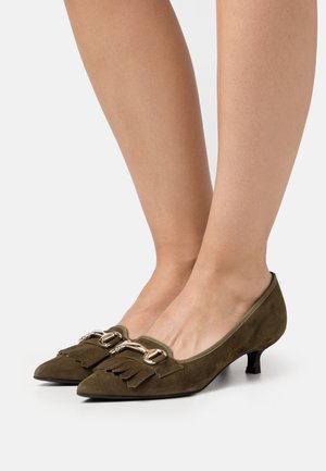 Olivengrønne ruskinds pumps med spids tå, dekorative frynser og guldfarvede hardware-detaljer, med en diskret lav hæl.