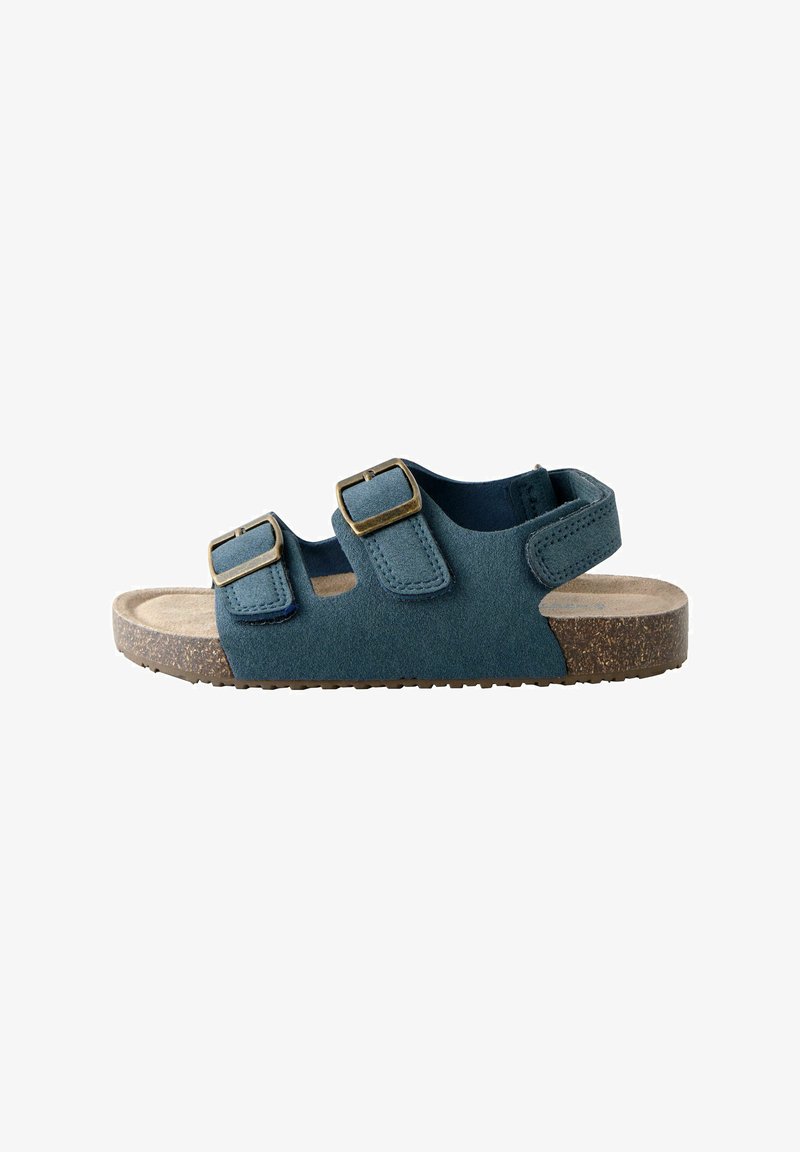 Teal nubuck sandal med to justerbare remme og messinglås, med en struktureret beige indersål og brun gummisål.
