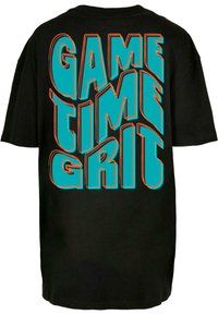 Svart oversized t-skjorte med dristig, stilisert tekst i turkis og oransje som leser "GAME TIME GRIT" på ryggen.
