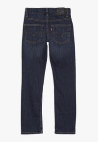 Vaqueros de mezclilla de color azul oscuro con un diseño de pierna recta, que cuentan con dos bolsillos traseros, detalles de costura y una etiqueta de cuero de la marca en la cintura.