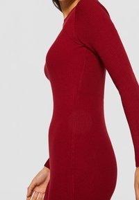 Figurbetontes Rippkleid in tiefrot mit langen Ärmeln, Rundhalsausschnitt und einer glatten Textur mit vertikalen Nähten.