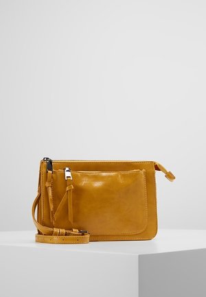 Sac bandoulière en cuir jaune avec une poche avant, fermeture éclair, sangle réglable et texture lisse. Design minimaliste sans logos visibles.