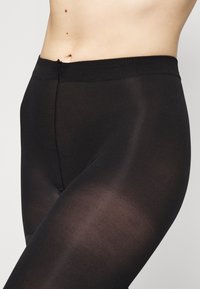 Black leggings made of smooth, stretchy fabric, featuring a high waistband and a seamless design that contours to the body.
