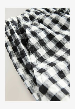 Sort-hvidternet stof med blød tekstur, udstyret med en samlet elastisk talje og synlige sømme.