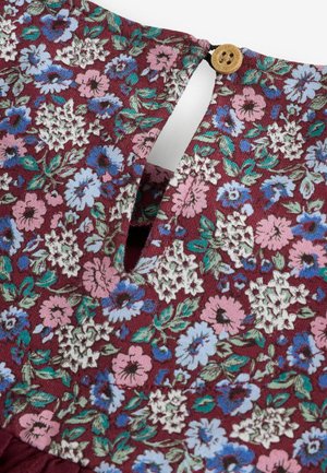 Abito floreale con sfondo bordeaux e fiori rosa, blu e bianchi; presenta un'apertura a chiave e un bottone decorativo in legno.