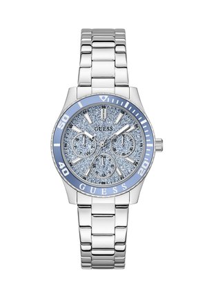 Ασημένιο μεταλλικό ρολόι χειρός με καντράν μπλε με γκλίτερ, τρεις υποκαντράν, φωσφορίζοντες δείκτες ώρας και γαλάζιο στεφάνι με αριθμούς και λογότυπο GUESS.