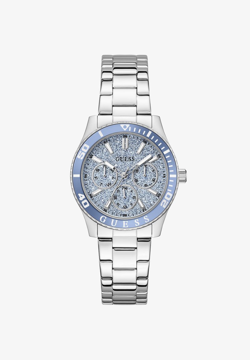 Ασημένιο μεταλλικό ρολόι χειρός με καντράν μπλε με γκλίτερ, τρεις υποκαντράν, φωσφορίζοντες δείκτες ώρας και γαλάζιο στεφάνι με αριθμούς και λογότυπο GUESS.