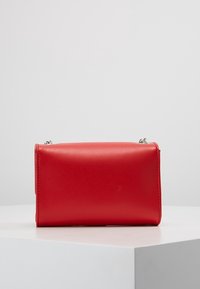Borsa a tracolla in pelle rossa con un design elegante, forma rettangolare, superficie liscia, hardware in argento e chiusura con zip.