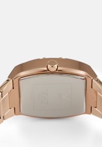 Rechteckige roségoldene Uhr mit poliertem Metallband, hervorgehobenem Kronenmechanismus und gebürstetem Stahlgehäuse. Verfügt über eingravierte Marken- und Wasserdichtigkeitsinformationen.