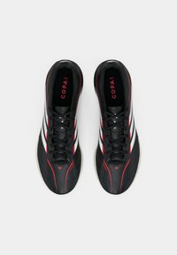 Μαύρα αθλητικά παπούτσια με κόκκινες λεπτομέρειες, λευκές ρίγες, κομψό σχέδιο και λεία υφή. Περιλαμβάνονται κορδόνια και επενδεδυμένος γιακάς.