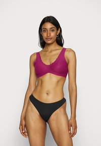 Lilla blondet bralette med bølgete kanter, med en sømløs design. Kombinert med svarte høyt utskårne truser. Jevn tekstur gjennom hele.