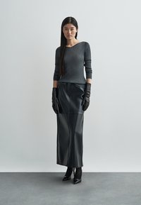 Gray ribbed long-sleeve top paired with a black leather ankle-length skirt, black gloves, and pointed heels, set against a neutral background.